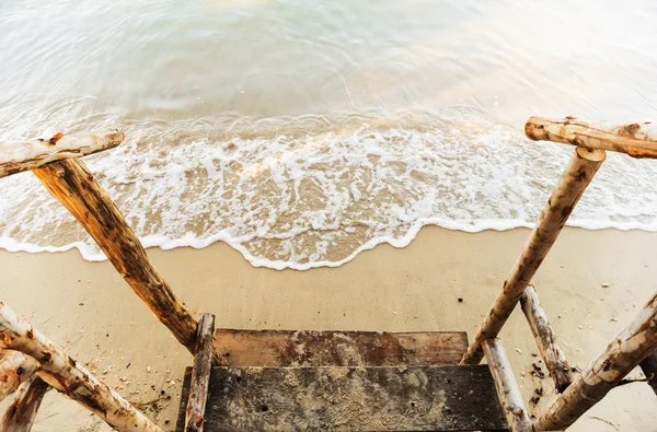 Wooden railing with sand beach in morning light — Stock Photo, Image