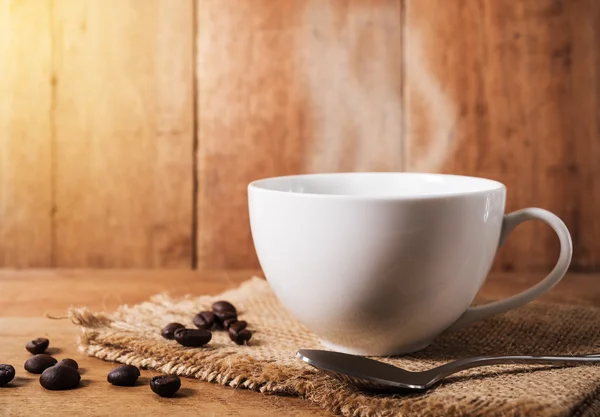 Xícara de café com feijão de café na mesa marrom — Fotografia de Stock
