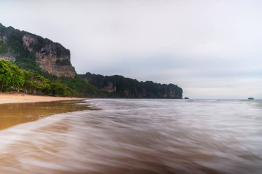 Sahilde gün batımı ya da gün doğumu. Gökyüzü ve bulutlarla dolu. Alacakaranlıkta gün ışığıyla birlikte.