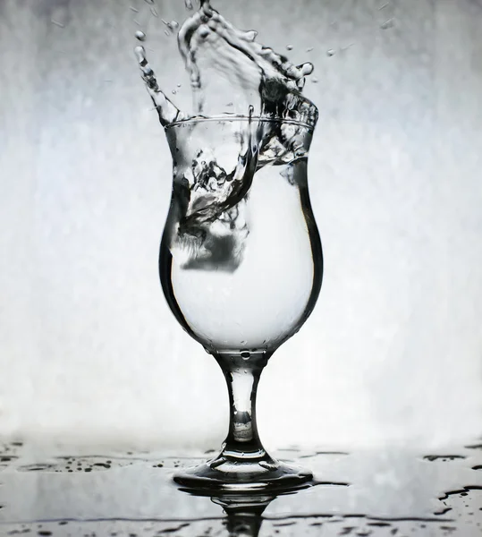 Eiswürfel, die in ein Glas Wasser spritzen, Stillleben, Grunge-Hintergrund — Stockfoto