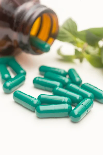 Pillole capsula verde fuoriuscita da una bottiglia — Foto Stock