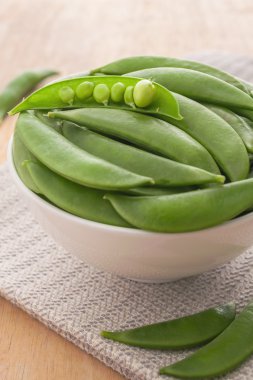 Ahşap üzerinde beyaz kase taze bezelye