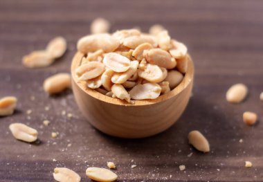 Tahta bir fincanda yer fıstığı doğal ahşap zeminde dinleniyor, sıcak ve kırsal bir yemek temalı sahne yaratıyor, Top View