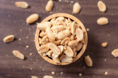 Tahta bir fincanda yer fıstığı doğal ahşap zeminde dinleniyor, sıcak ve kırsal bir yemek temalı sahne yaratıyor, Top View