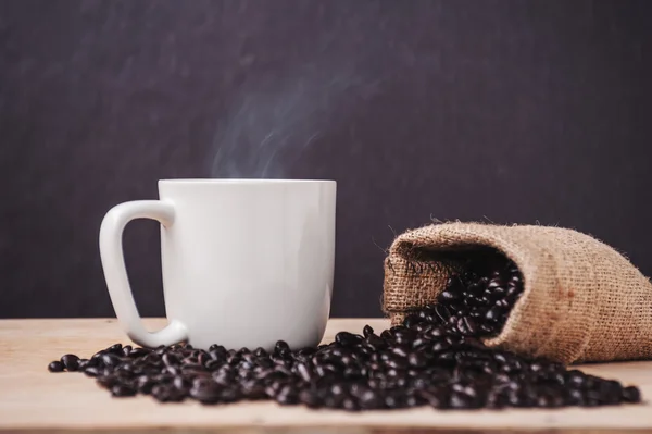 Tazza di caffè con caffè tostato su un legno scuro e fumo — Foto Stock