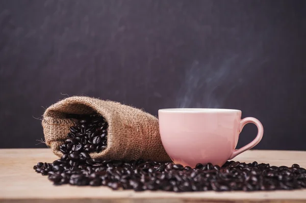 Tazza di caffè con caffè tostato su un legno e fumo — Foto Stock