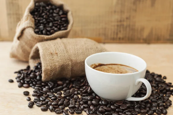 Xícara de café com grão de café em madeira — Fotografia de Stock