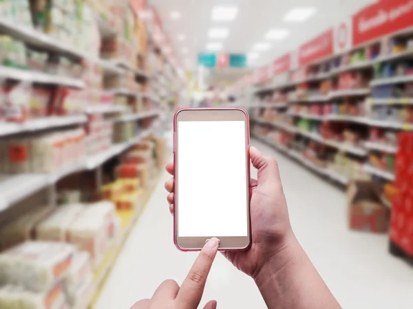 デパートのバック グラウンドでのスマート フォンと手がぼやけています。 — ストック写真
