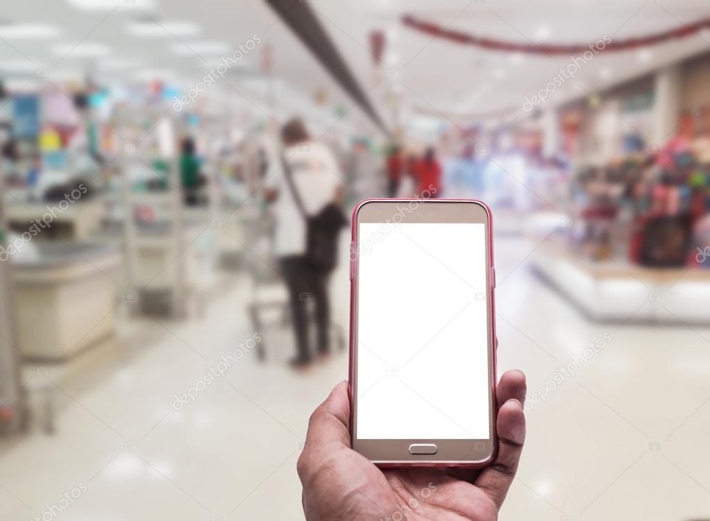 Hand with smartphone on blurred in shopping mall background