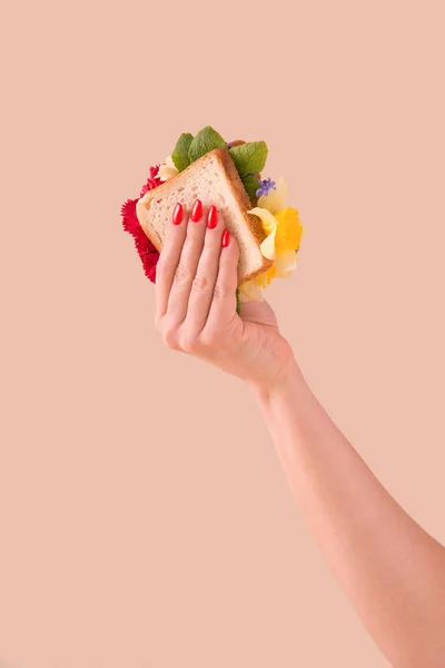 Mulher Mão Segurando Sanduíche Com Flores Coloridas Frescas Fundo Pastel — Fotografia de Stock