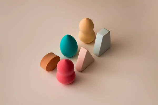 Pattern made of makeup sponges pastel colors on beige background. Minimal shapes creative concept.