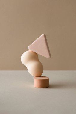 Soyut dengeleyici geometrik kompozisyon ile pastel bej arka planda makyaj süngerleri ve yumuşak gölgeler. Kopyalama alanı olan minimal sanat.
