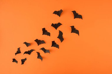 Flying or levitate concept with halloween bats on orange background. Minimal bold composition with copy space.