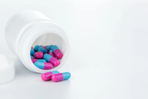 Skyblue and pink pills an pill bottle on white backgroun — стоковое фото