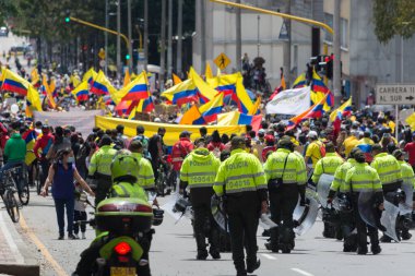 Bogota, Kolombiya; 9 Mayıs 2021: Kolombiya Ulusal Grev sırasında protestocular tarafından bayraklarla yapılan bir eylem sırasında ESMAD çevik kuvvet polisi sorgulandı ve protestocular onları cinayetlerle ilgili olarak suçladı.