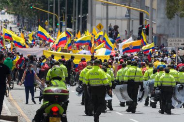 Bogota, Kolombiya; 9 Mayıs 2021: Kolombiya Ulusal Grev sırasında protestocular tarafından bayraklarla yapılan bir eylem sırasında ESMAD çevik kuvvet polisi sorgulandı ve protestocular onları cinayetlerle ilgili olarak suçladı.