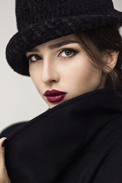 Brunette with hat in black clothes with red lips