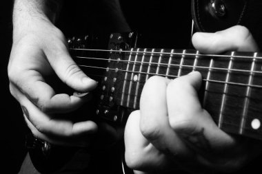 Siyah beyaz gitar çalan birinin elleri.