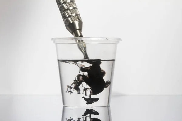 透明なガラスの中にきれいな水で黒いインクの針をきれいにタトゥーマシン — ストック写真