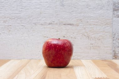 Tahta bir masada beyaz arka planı olan kırmızı bir elma.
