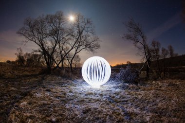 Gece gökyüzü zemin karşı Nehri'nin kıyısında ağaçta arasında parlayan topu