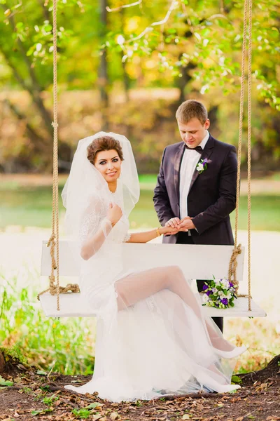 Жених и невеста на качелях на фоне осеннего пейзажа — стоковое фото