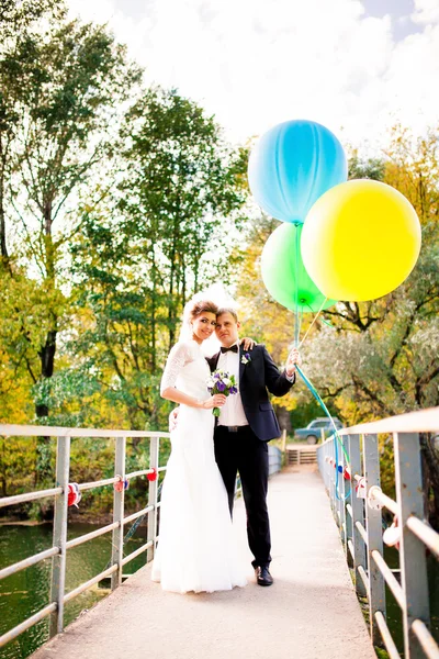 Mariée et marié embrassant sur le pont avec des ballons — Photo