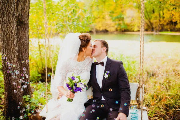Les mariés sur une balançoire et des bulles volantes — Photo