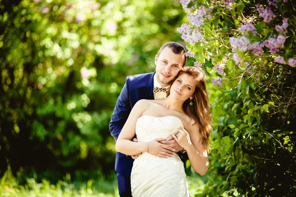 Brudgummen och bruden i maj, mot bakgrund av blommande natur — Stockfoto