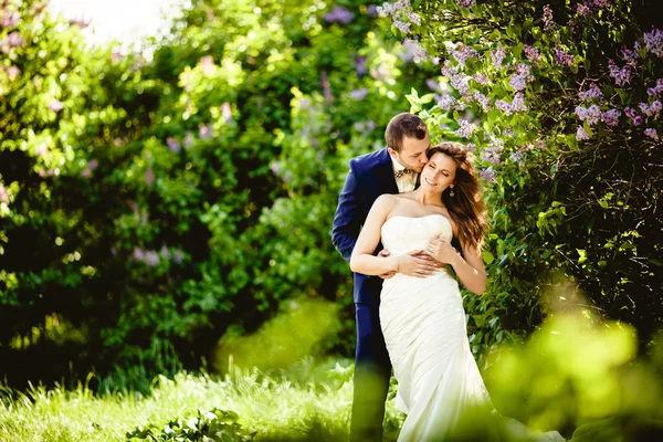 Brudgummen och bruden i maj, mot bakgrund av blommande natur — Stockfoto