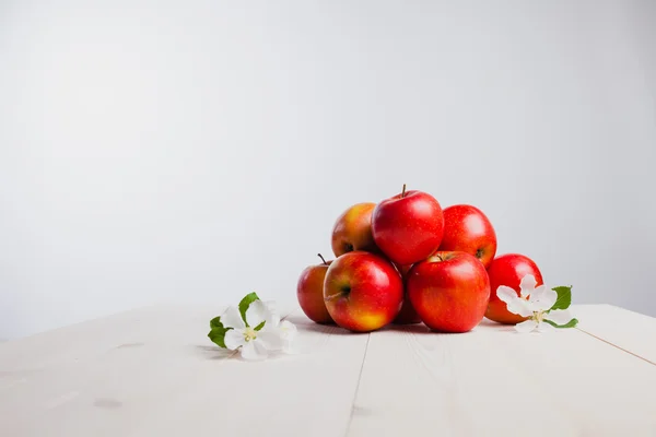 A few red apples on a white background  with flowers — Stock Photo, Image
