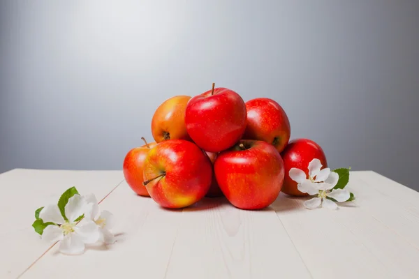 A few apples on a white wooden surface with flowers — Stock Photo, Image