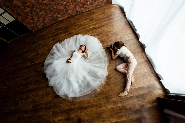 Jovem fotógrafo sexy está tirando fotos da noiva no estúdio — Fotografia de Stock