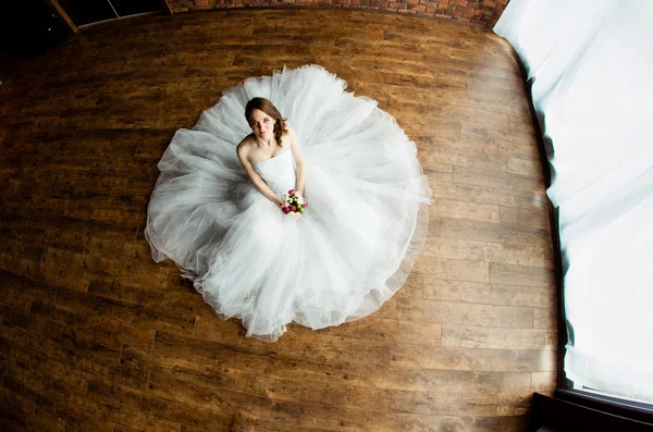 Jonge sexy bruid in de studio zit op de houten vloer — Stockfoto