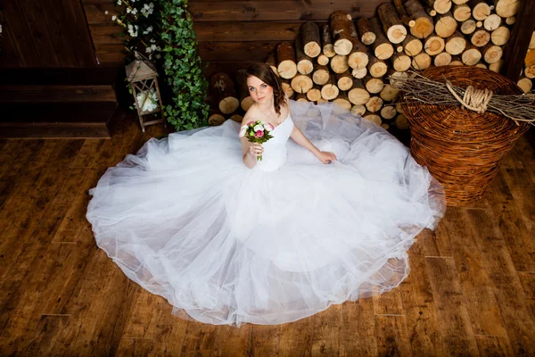 Jovem noiva sexy no estúdio está sentado no chão de madeira — Fotografia de Stock