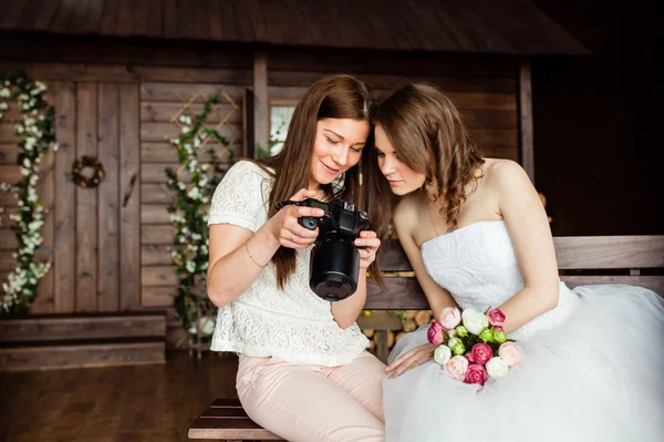 Mladá sexy fotograf ukazuje, že nevěsta přinesl fotografie — Stock fotografie