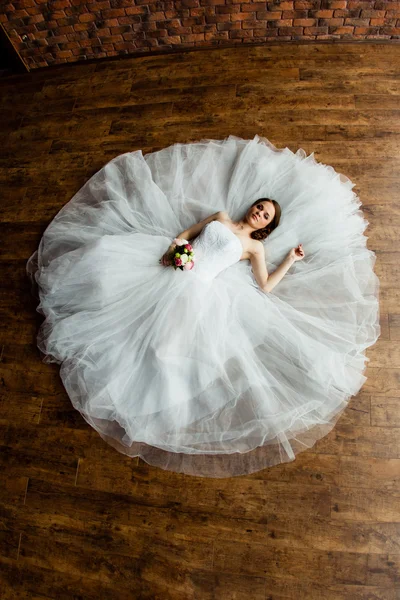 Молодая сексуальная невеста в студии лежит на деревянном полу — стоковое фото