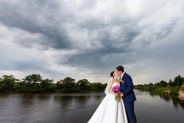 Der Bräutigam küsst die Braut am Ufer des Flusses — Stockfoto