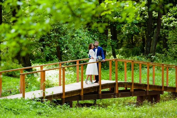 Bruid en bruidegom lopen op een houten brug — Stockfoto