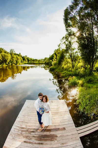 Les mariés sont debout sur une jetée en bois près de l'étang — Photo