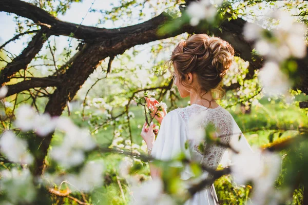 Junge Braut mit blonden Haaren posiert vor dem Hintergrund des Frühlings Obstgarten — Stockfoto