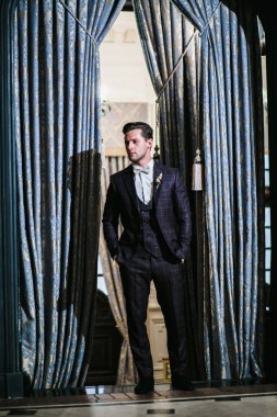 Damat, klasik iç mekanın arka planında düğün öncesi poz veriyor.