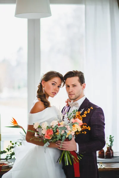 Piękna i stylowa para nowożeńców pozuje z bukietem ślubnym — Zdjęcie stockowe