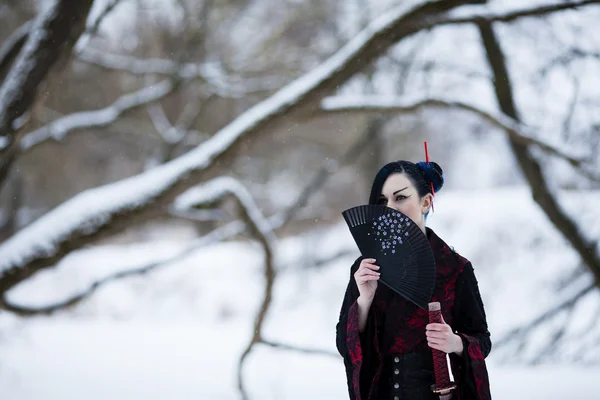 Beautiful young girl in a suit of samurai on the frozen river — Stock Photo, Image