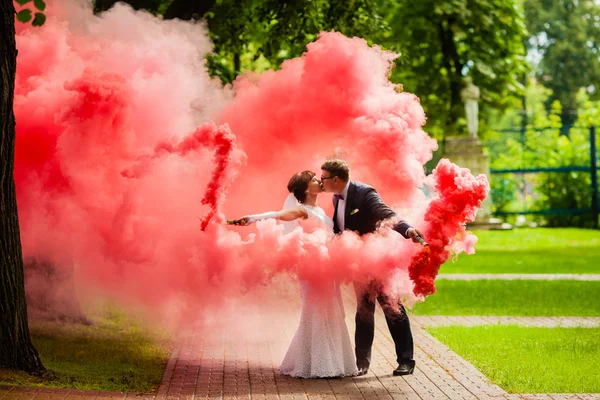 Sposa e sposo con un fumo rosso brillante — Foto Stock