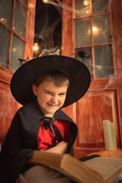 the boy in wizard\'s hat on a background of red open doors, halloween