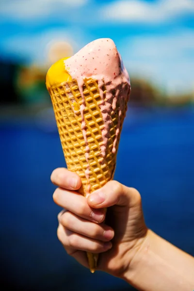 Cone de sorvete sendo realizada contra uma paisagem urbana de verão — Fotografia de Stock