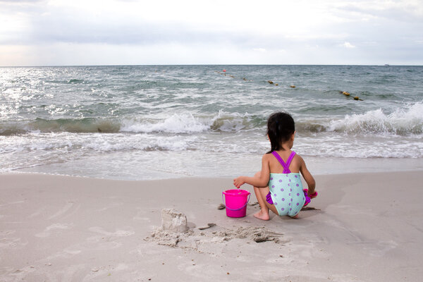 Азиатская маленькая китайская девочка играет с пляжными игрушками

