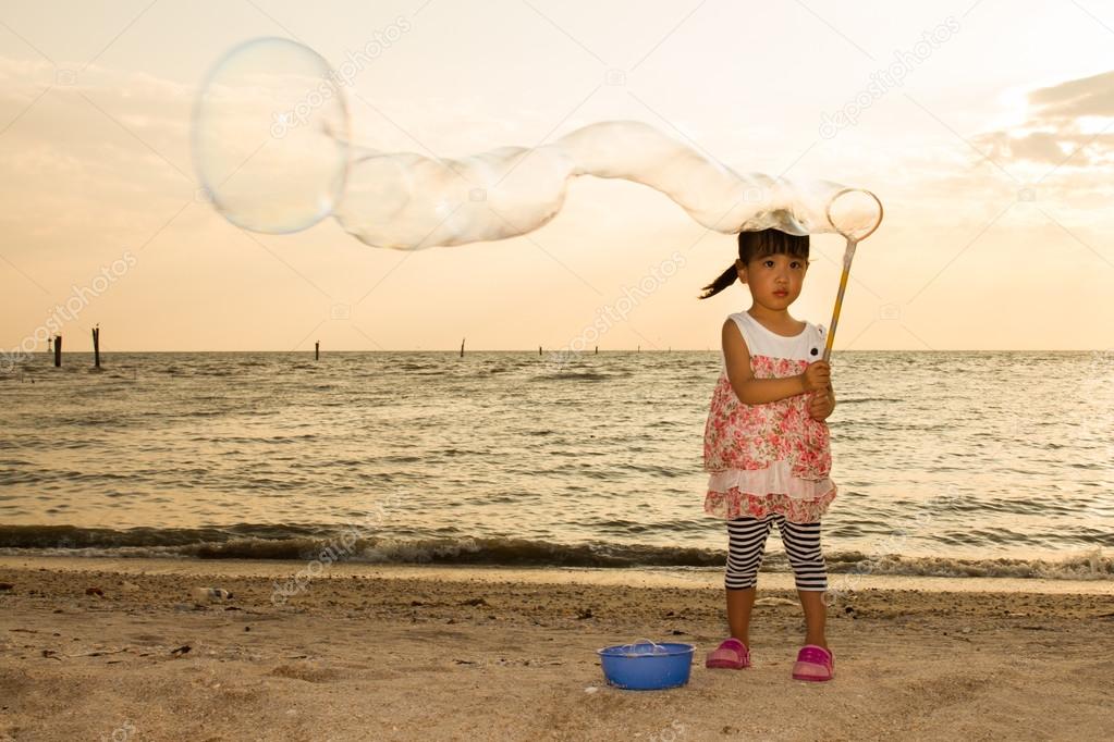 Asian Little Chinese Girl Playing Soap Bubbles on the Beach