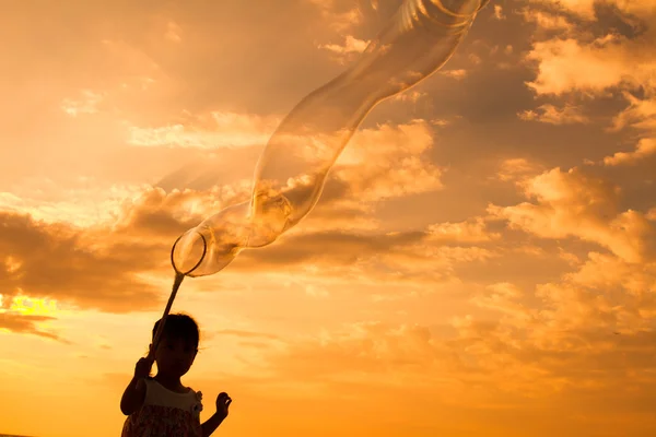 Asijské malá čínská dívka hrající mýdlové bubliny na pláži — Stock fotografie